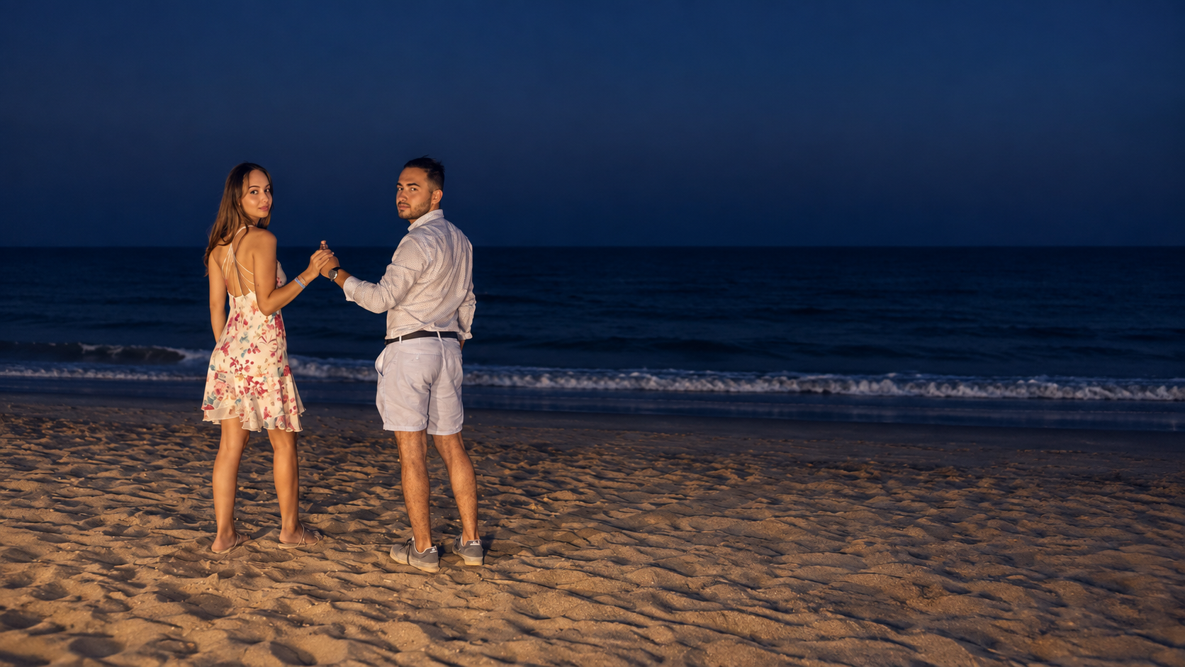 Cristi și Bianca ținându-se de mână pe plajă — fotografie retușată
